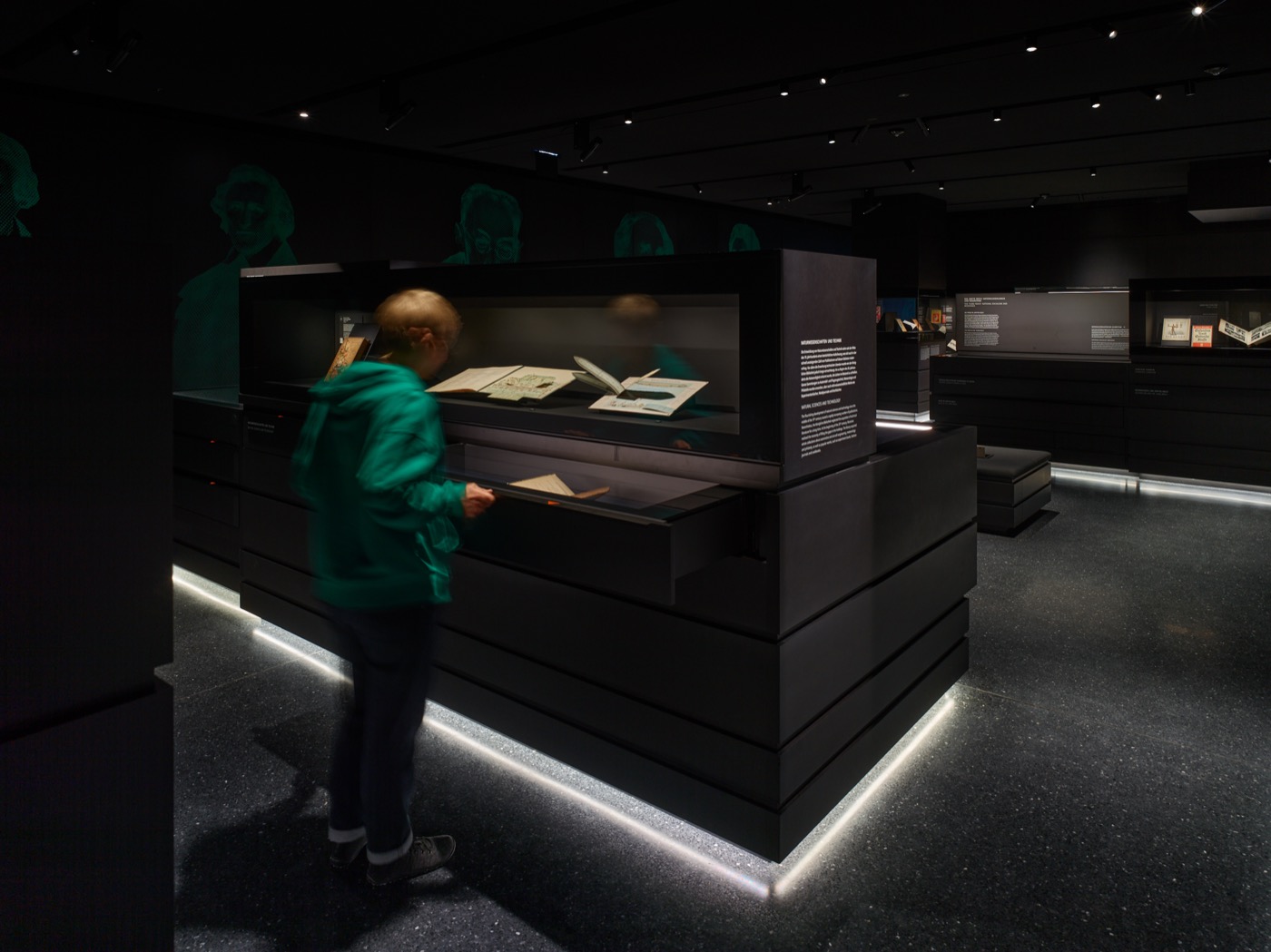 Dauerausstellungsbereich im Stabi-Kulturwerk mit großen Vitrinenkörpern in schwarz mit Sockelunterleuchtung und Frontvitrinen mit integrierter Beleuchtung und Schubläden mit integrierter Beleuchtung